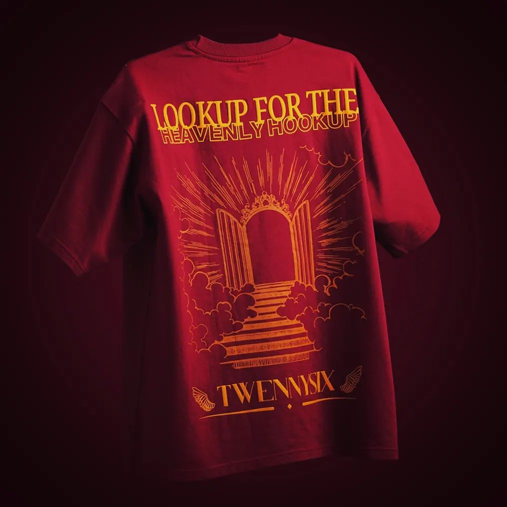 Flat lay view of the backside of the Twennysix Heavenly Hookup T-shirt, showcasing the intricate design featuring a heavens gate illustration and the phrase "Lookup for the Heavenly hookup" in bold yellow lettering against a maroon background.