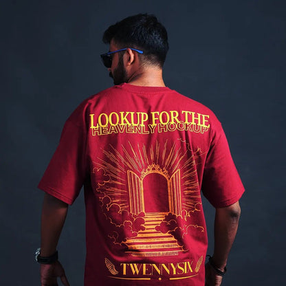 A model displaying the backside of the Twennysix Heavenly Hookup T-shirt, revealing the striking depiction of a heavens gate and the phrase "Lookup for the Heavenly hookup" in bold lettering.