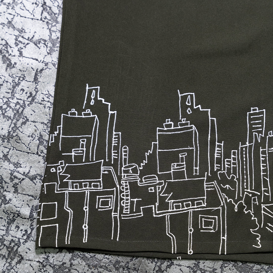 Close-up view of the intricate embroidery depicting buildings on the Skyscraper Shirt.